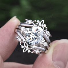 a person holding a diamond ring in their hand with the center surrounded by smaller diamonds