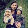 a woman and two children are sitting in the grass with their arms around each other