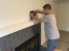 a man is painting a brick fireplace with an electric paint roller and a power drill