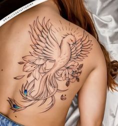 a woman laying on top of a bed with a bird tattoo on her back shoulder