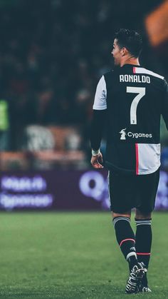 a soccer player in black and white uniform standing on the field with his foot up