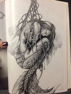 an open book with a drawing of a woman wrapped in chains and holding her head