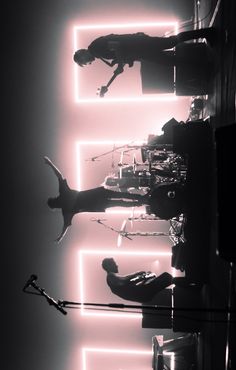 black and white photograph of people standing in front of neon lights on the wall behind them