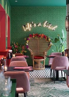 the interior of a restaurant with pink chairs and green walls