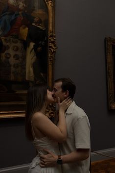 a man and woman kissing in front of a painting