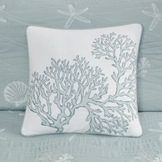 a white pillow with blue corals and starfish on it sitting on a bed