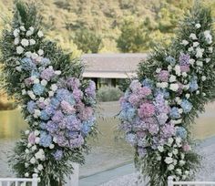 two floral arrangements are arranged in front of a lake