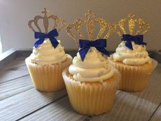 three cupcakes with white frosting and royal crowns on top are sitting next to each other