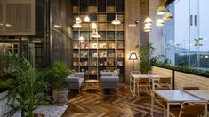 a restaurant with tables and chairs, plants on the wall and bookshelves in the background