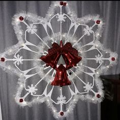 a white christmas wreath with red bells and snowflakes hanging from it's sides