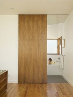 a bathroom with wood flooring and a white bathtub next to a wooden door