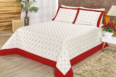 a white and red bed in a bedroom next to a table with flowers on it