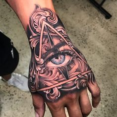 a hand with an all seeing eye tattoo on it