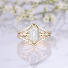 a close up view of a diamond ring on a white surface with flowers in the background