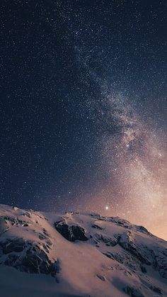 the night sky is filled with stars above snow covered mountains and rocks in the foreground