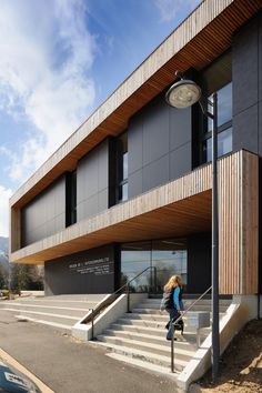 a woman is walking up the stairs to a building that has wooden panels on it