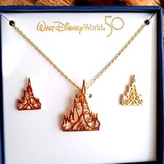 This Is A Beautiful Jewelry Set That Includes A Castle Pendant And Chain With Matching Castle Earrings. Set In A Gold Toned Metal With 10 Crystal's For Windows In The Pendant And The Number 50 Forming The Door. Each Earring Has 3 Crystal's. Comes In A Commemorative Blue Box With A Gold Castle With A 50 Logo. This Is A Perfect Set For That Disney Collector In Your Family Themed Jewelry For Disney Fan Events, Disney Gold Earrings As Gift, Disney Gold Earrings For Gift, Gold Disney Earrings For Gift, Gold Castle, 50 Logo, Walt Disney World 50th Anniversary, Tangled Necklace, Disney World 50th Anniversary