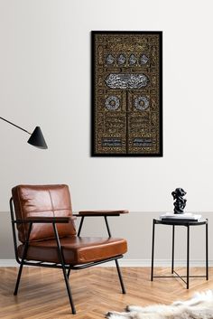 a chair and table in a room with a wall hanging on the wall behind it