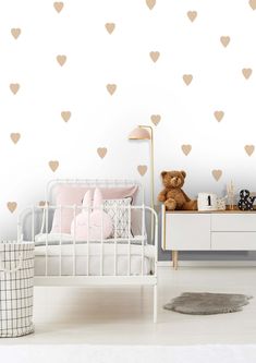 a child's room with hearts on the wall and a teddy bear sitting in bed