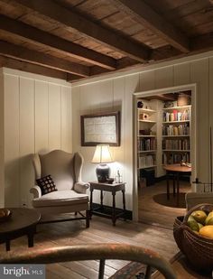 a living room filled with furniture next to a book shelf and a lamp on top of a table