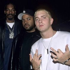 three men standing next to each other with their hands in the air and one man wearing a white shirt