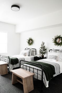 two beds in a room with black and white bedding, wreaths on the wall