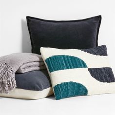 pillows and blankets are sitting on a white surface with black, gray, and blue accents