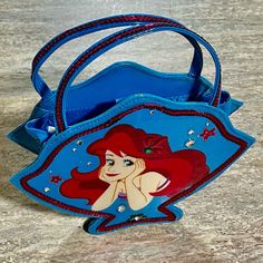 the little mermaid purse is blue and has red hair