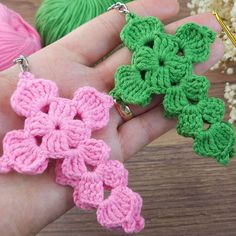 two crocheted flowers are being held in the palm of someone's hand