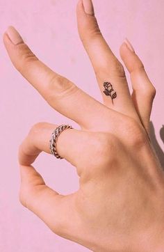 two hands with tattoos on their fingers and one has a flower tattoo on the middle finger