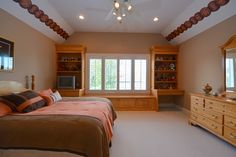 a bedroom with a bed, dresser and window in the corner is shown at an angle