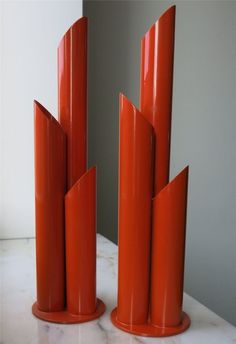 three orange vases sitting on top of a marble table