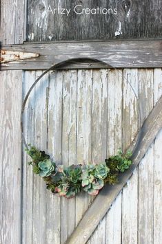 a heart shaped wreath with succulents hangs on the side of a barn door