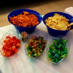 three bowls filled with different types of food on top of a white cloth covered table