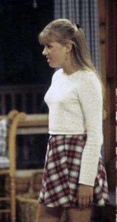 a woman in a plaid skirt and white sweater