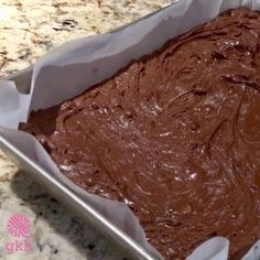 a pan filled with chocolate frosting on top of a counter