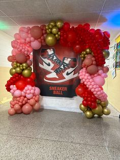 an arch made out of balloons in the middle of a hallway with a sneaker shoe sign on it