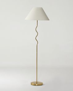 a gold floor lamp with a white shade on the base and a light bulb in the middle