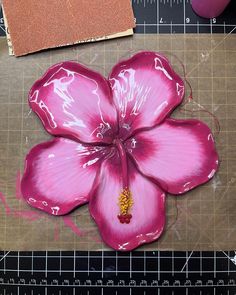 a pink flower sitting on top of a cutting board