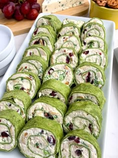 a white platter filled with rolls covered in spinach and cranberry sauce