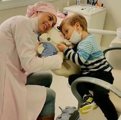 a woman holding a child in a dental room