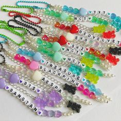 a bunch of beaded necklaces with words written on them in different colors and shapes