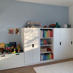 a white bookcase filled with lots of books next to a wall full of toys