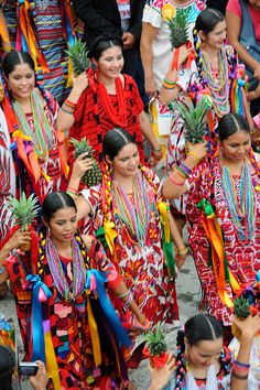 a group of people walking down a street next to each other wearing colorful clothing and holding pineapples