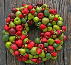 a wreath made out of apples, kiwis and limes on a wooden surface