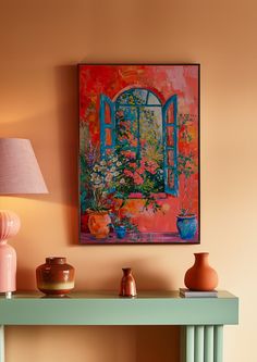 a painting on the wall above a table with vases