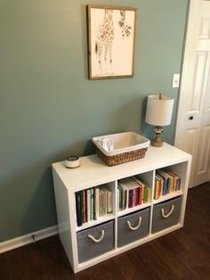 a white shelf with books and a basket on top