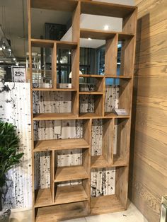 a wooden book shelf with many books on it in front of a wall mounted mirror