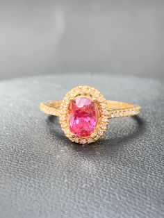 a close up of a ring with a pink stone in the center and diamond accents