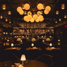 a dimly lit dining room with tables and lamps on the ceiling, along with many bookshelves